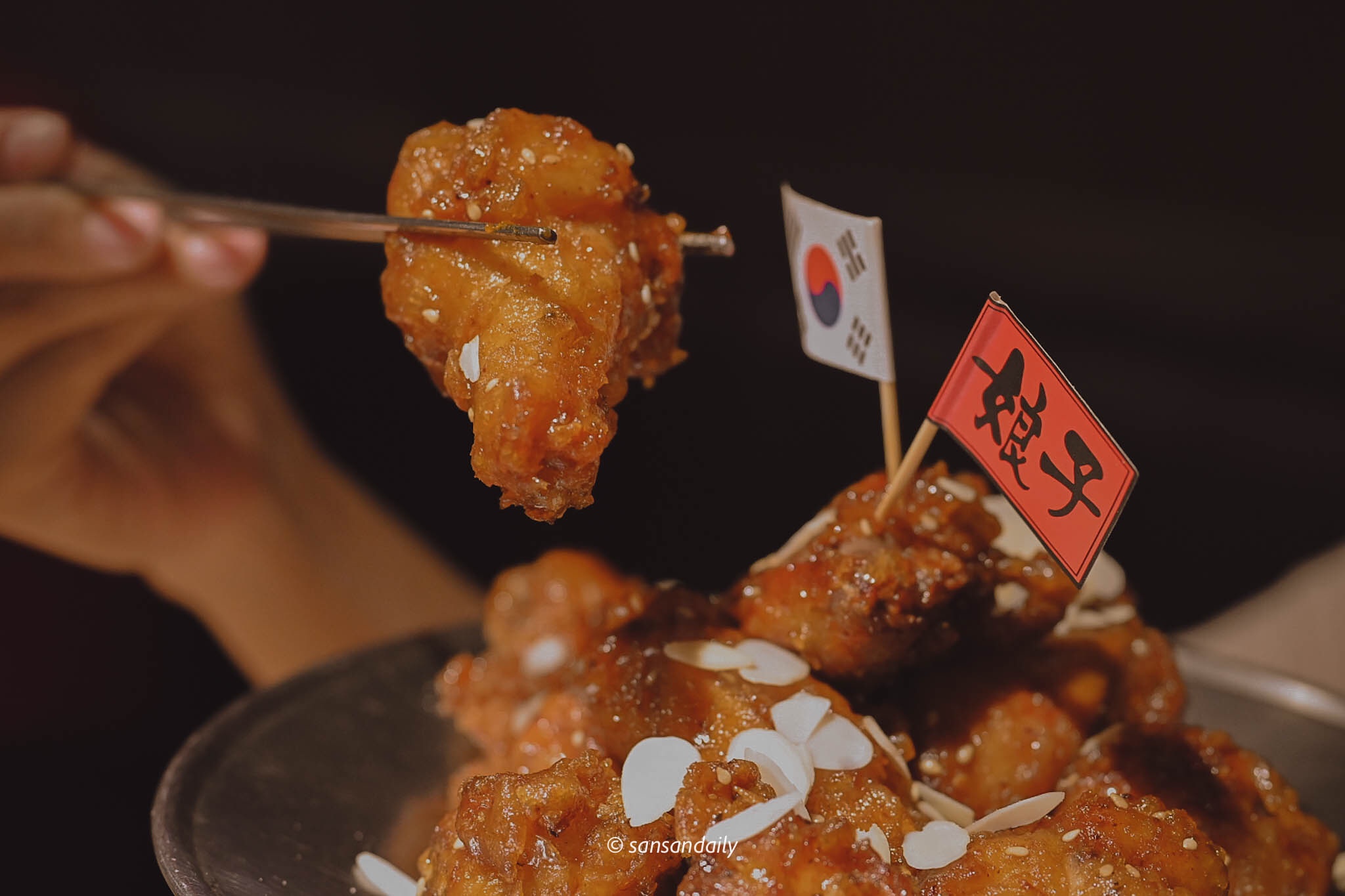 筷子夾著韓式蜂蜜炸雞的翅小腿