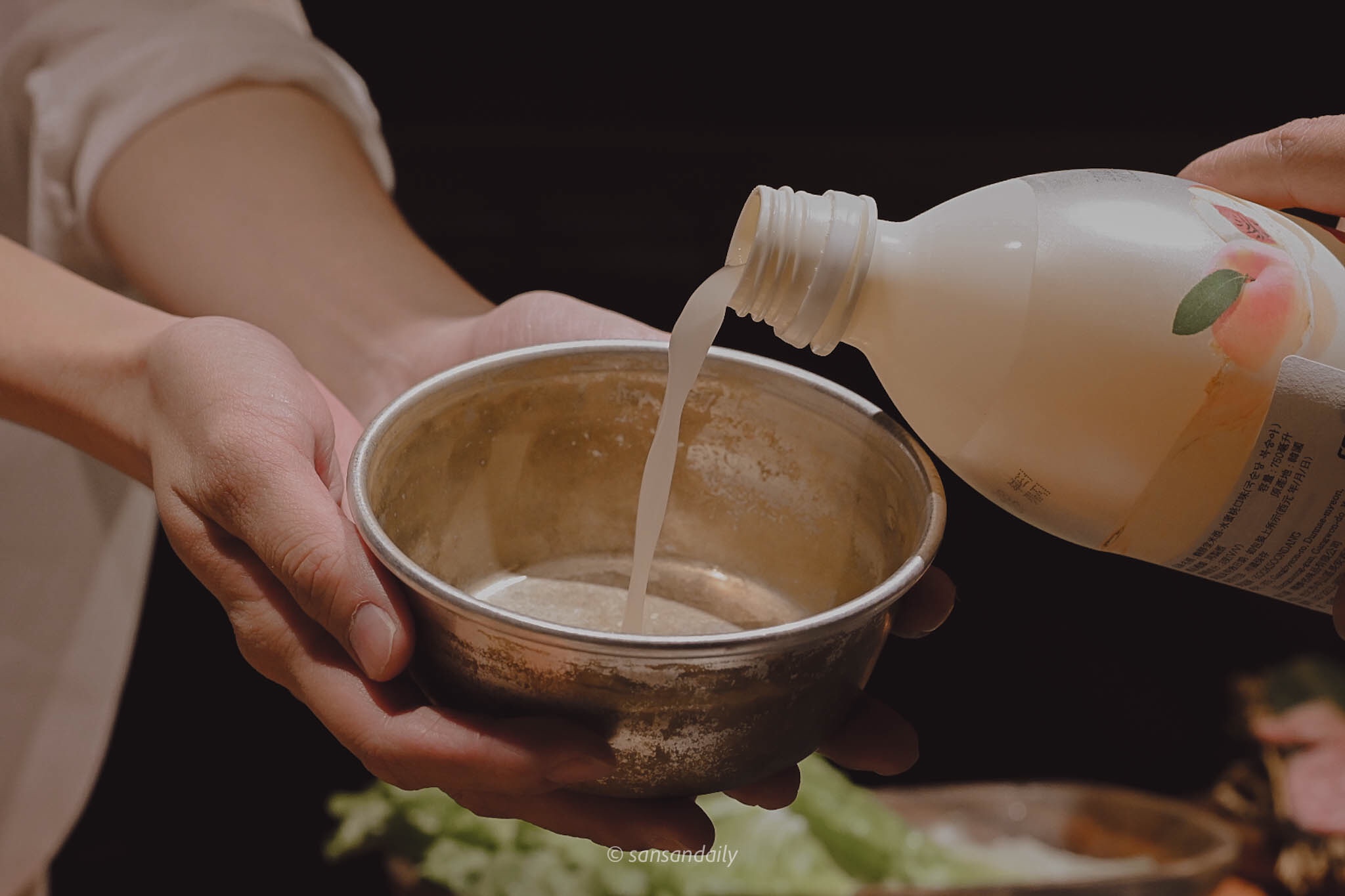 一個人捧著鋁碗 另一個人倒水蜜桃口味馬格利進去