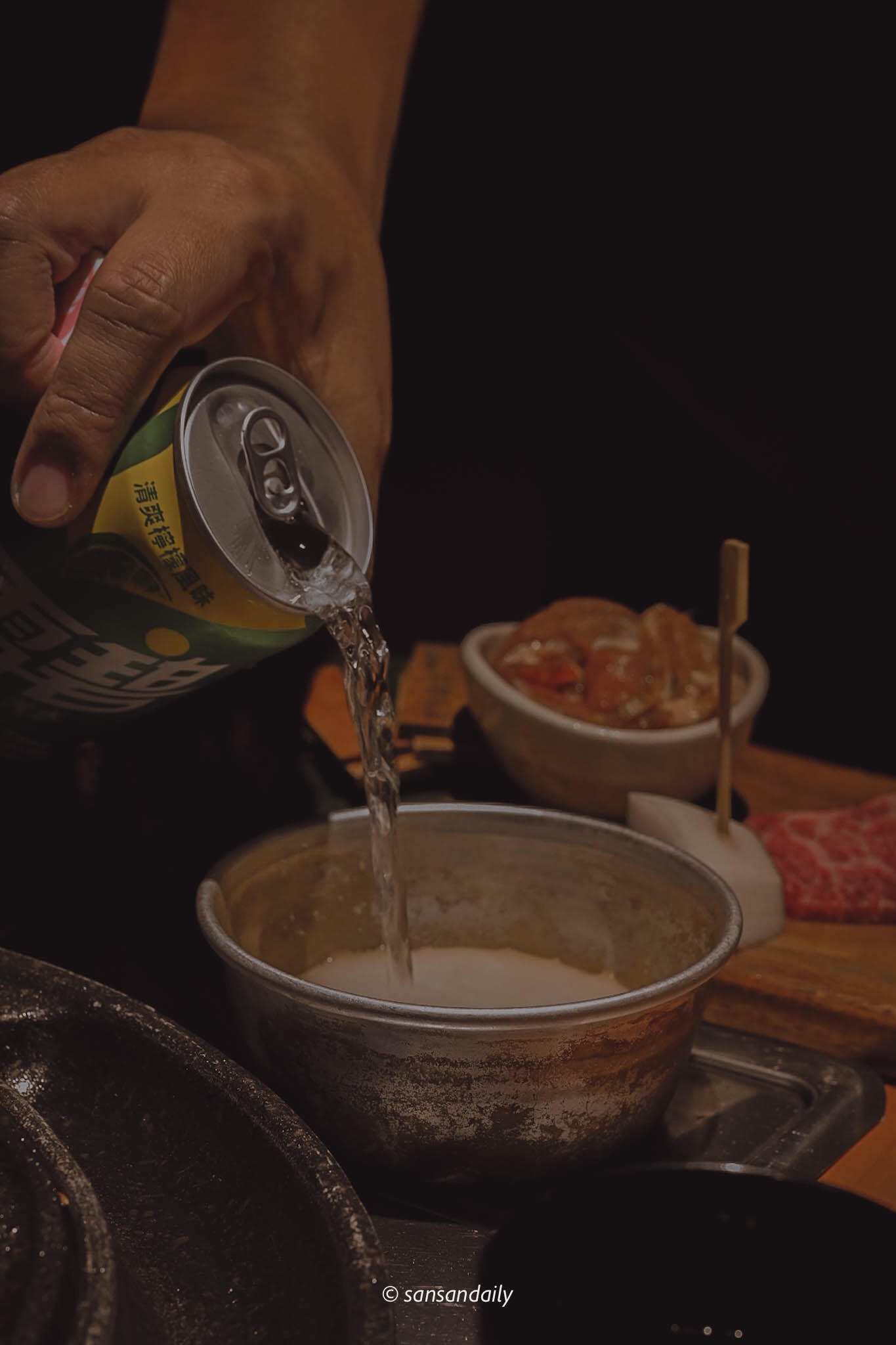 一個人將雪碧倒入在桌上的鋁碗