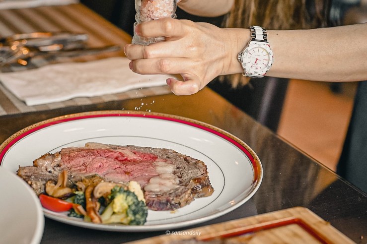 一位女子現磨海鹽在Mr.Tom爐烤肋眼牛排上