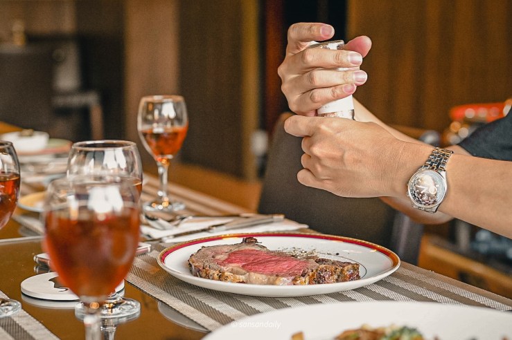 一位男子現磨海鹽灑在Mr.Tom爐烤肋眼牛排上