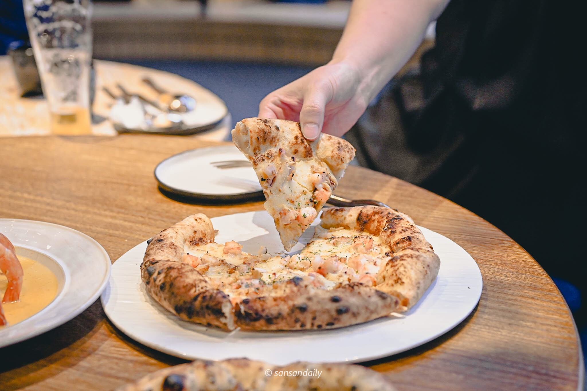 一隻手拿起一片GUMGUM Beer & Wings 金沙漁夫披薩 情境圖