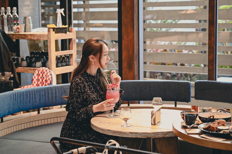 一位女子坐在GUMGUM Beer & Wings手扶一杯高腳杯調酒 向外看情境圖