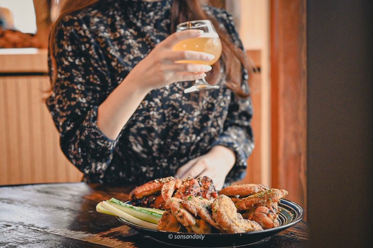 一位女子在GUMGUM Beer & Wings手拿高酒杯啤酒 桌上一盤雞翅