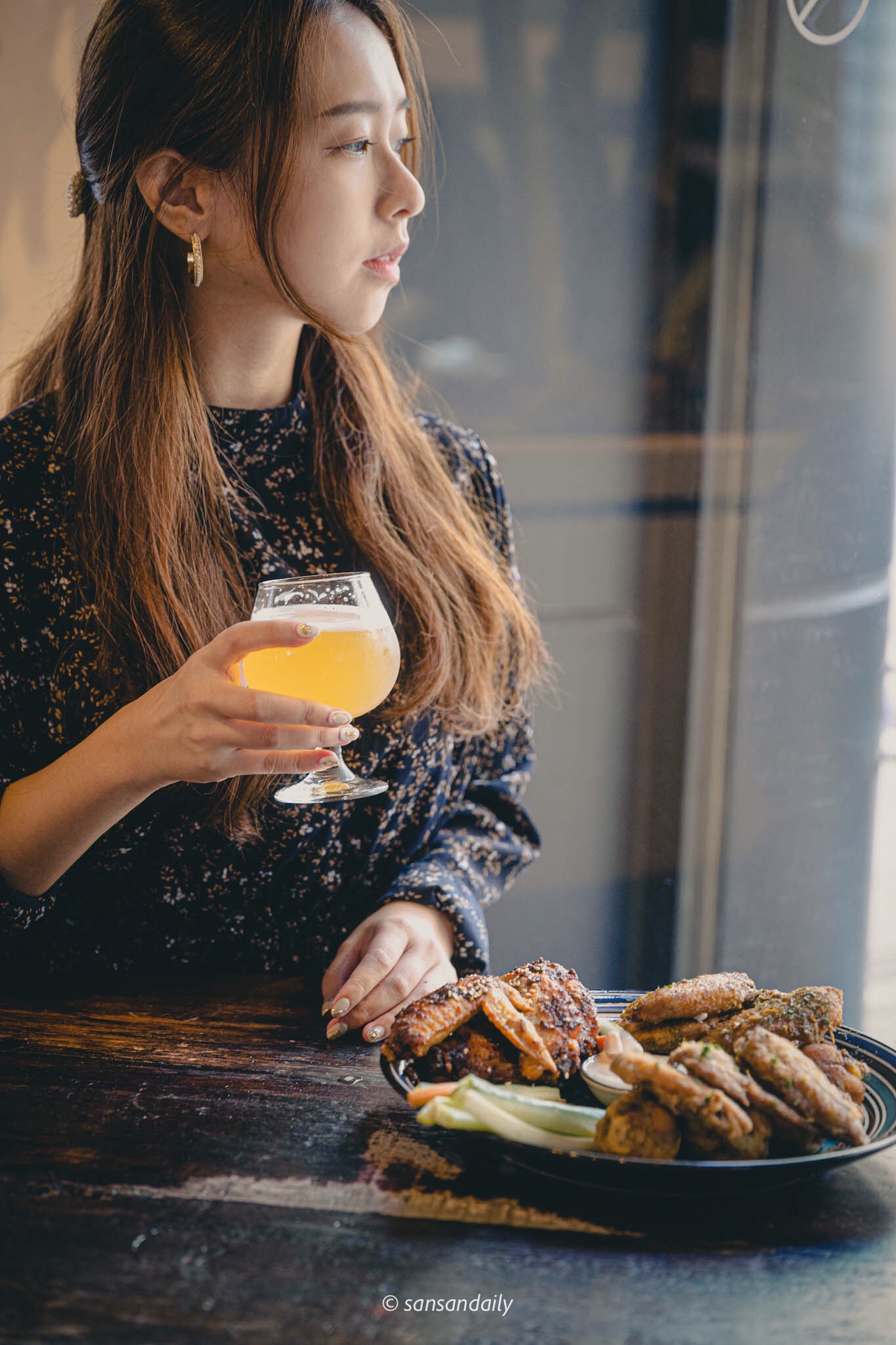 一位女子手拿高腳杯啤酒看向窗外情境圖