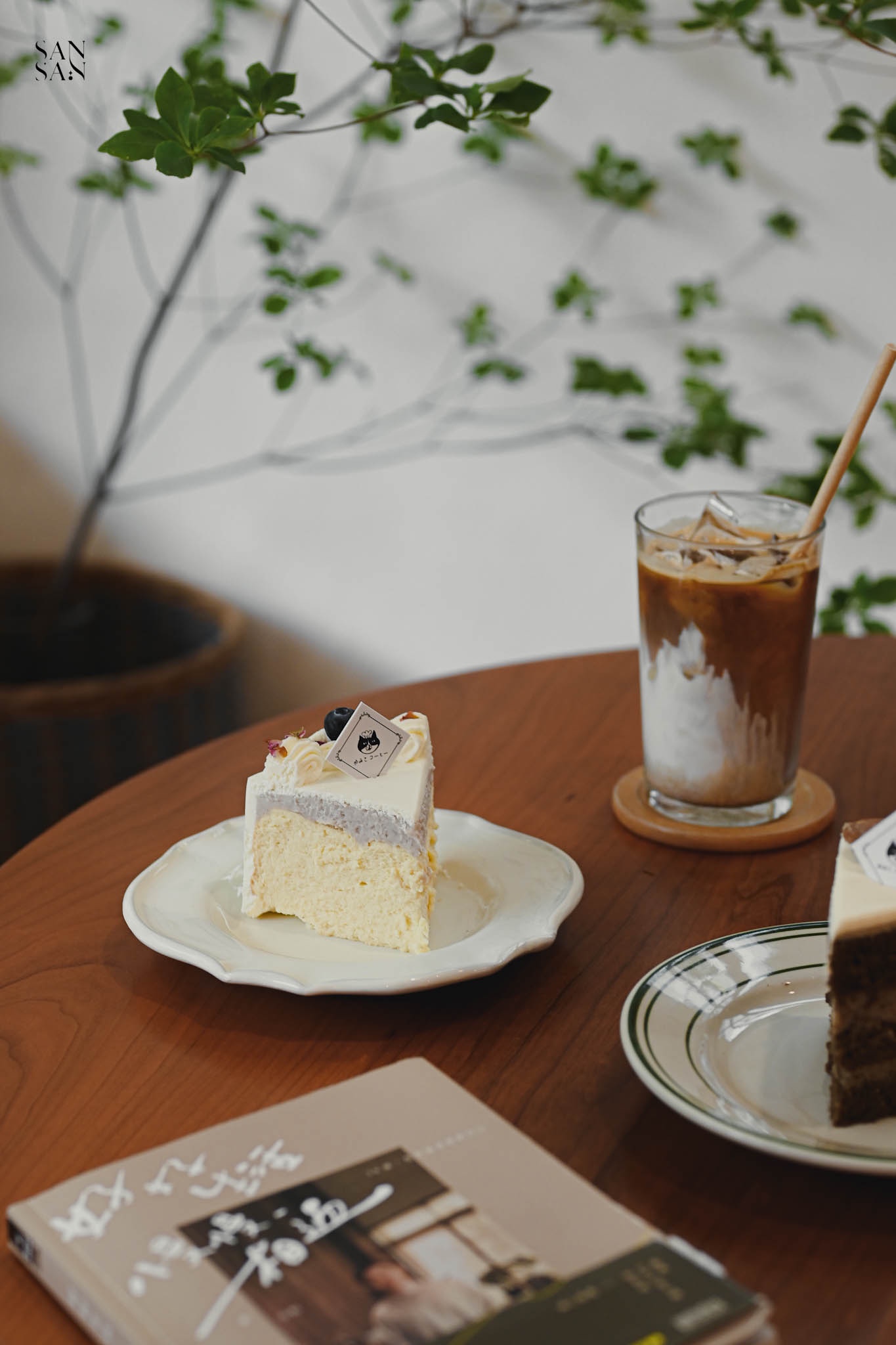 木桌上擺著一盤蛋糕 一杯飲料 一本書的畫面