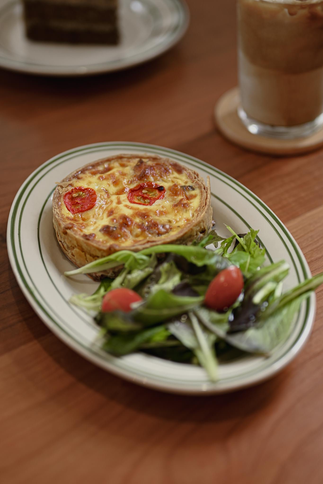 桌上的盤子中有一個圓鹹派旁邊附上生菜沙拉