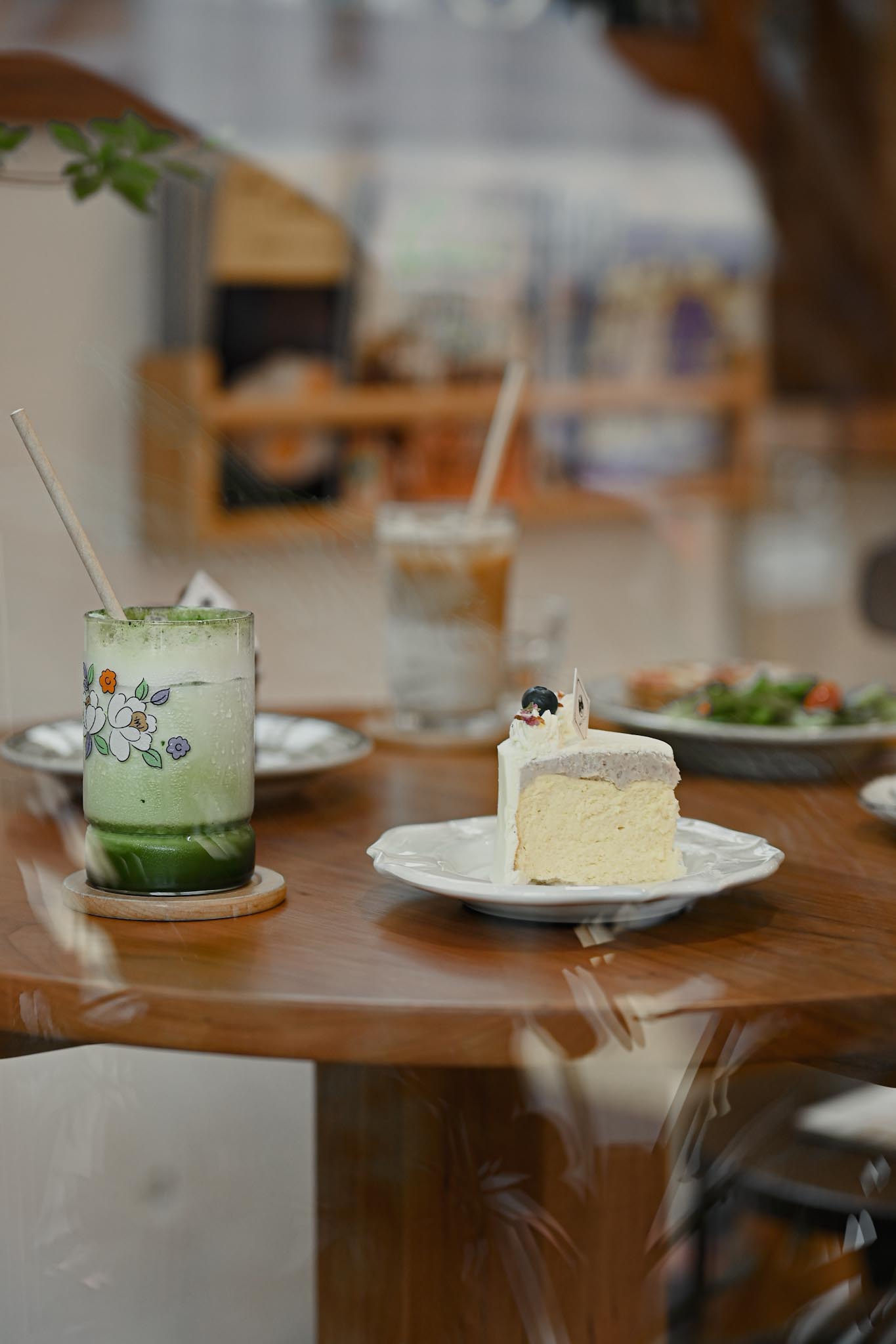 透過窗戶往內看 桌上擺著蛋糕和飲品