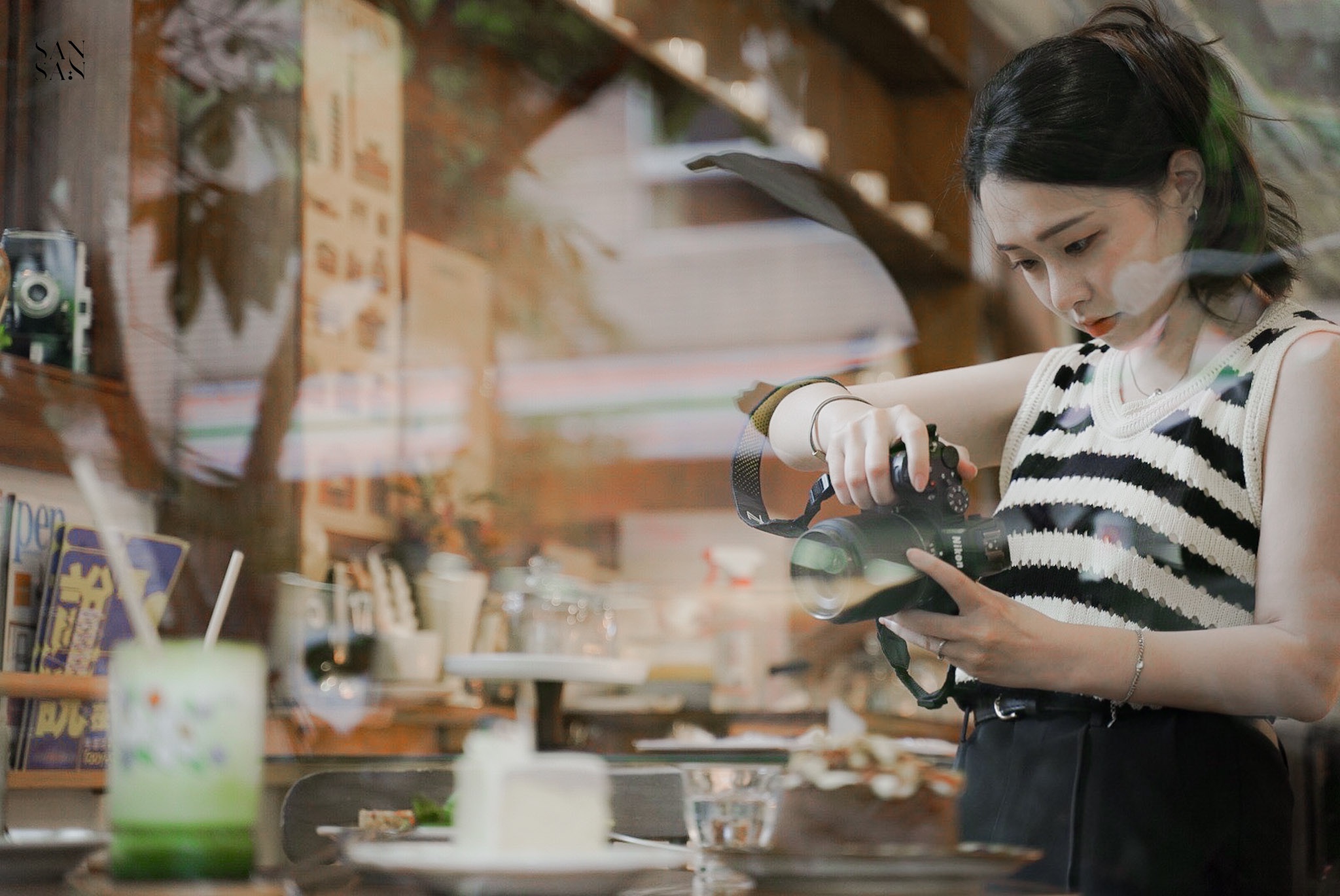 透過玻璃窗向內看 一位女子拿相機拍攝中