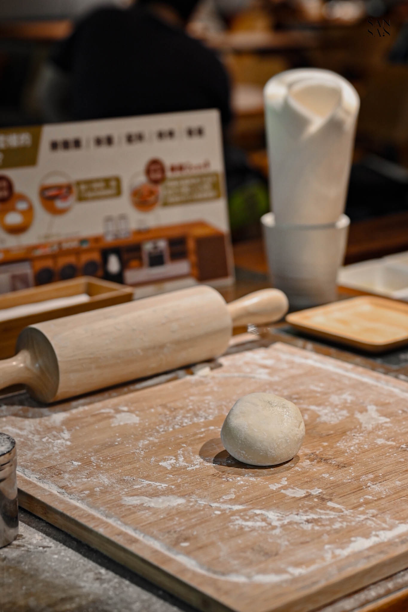木板上放著一團麵糰和一支桿麵棍
