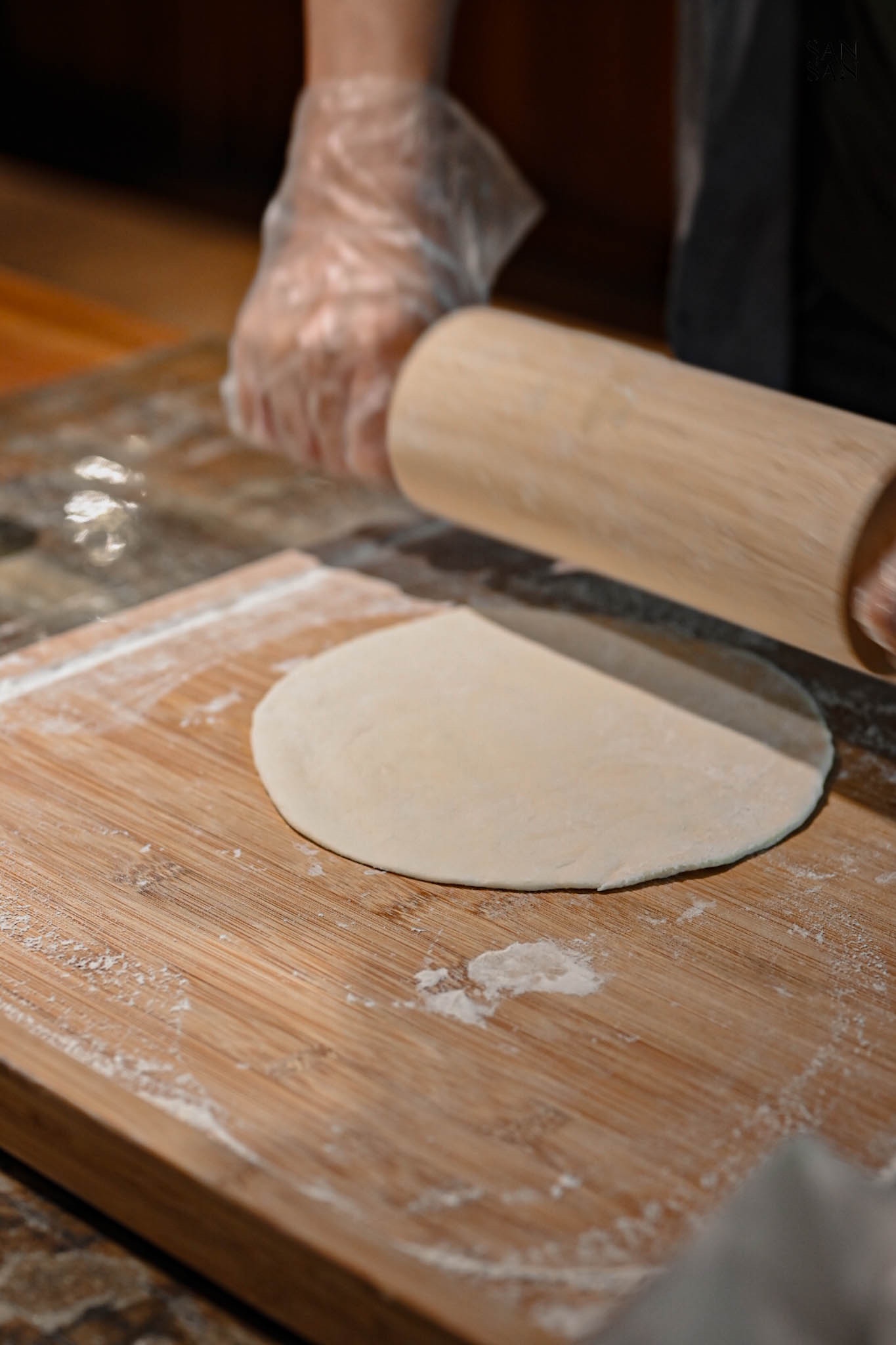 一雙手持桿麵棍 木板上有一個圓形麵皮
