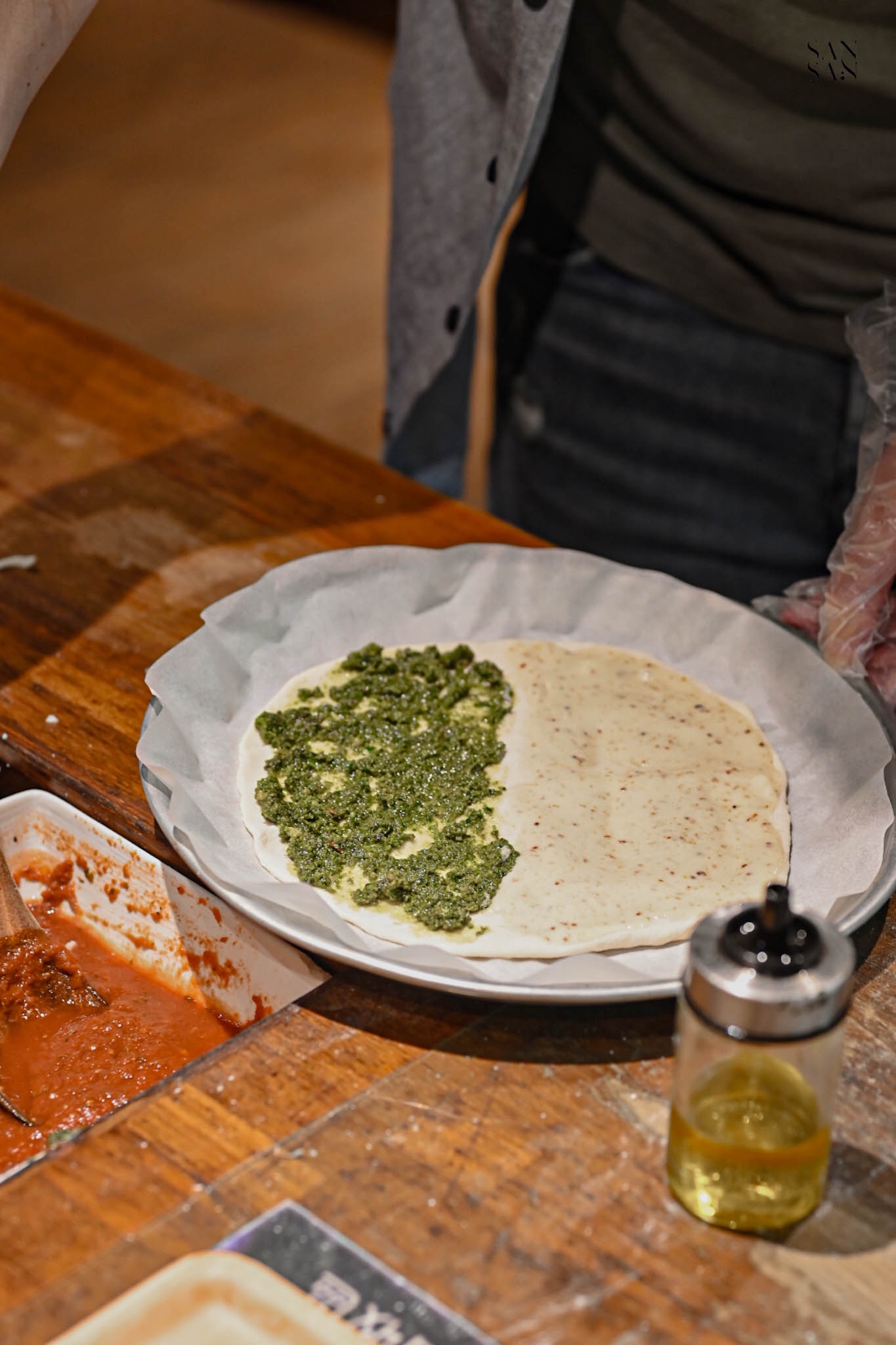 一盤麵糰上一半是青醬一半是白醬 桌上擺著一罐橄欖油