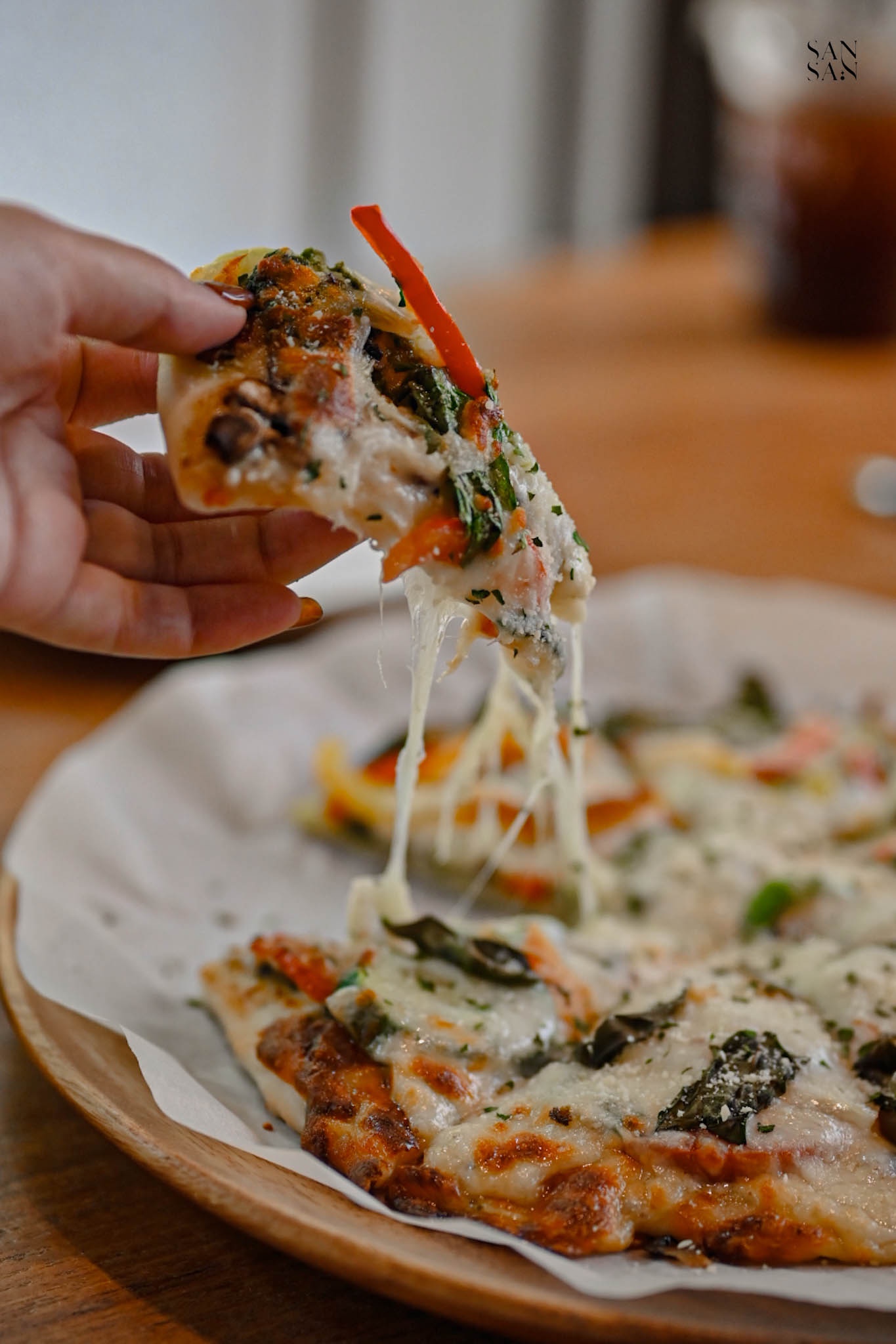 一隻手拿起一片牽絲披薩的畫面