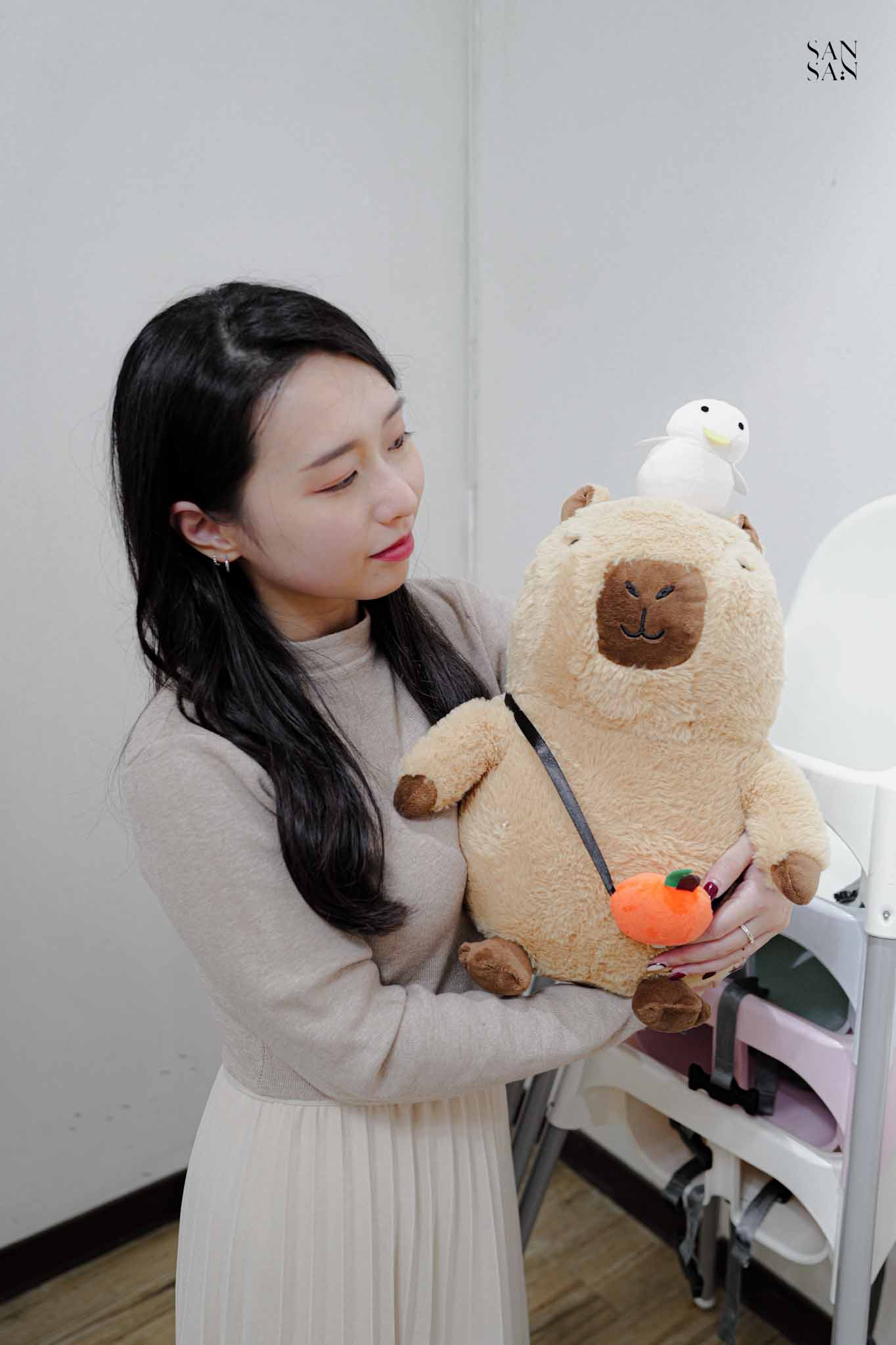 一個女人抱著一隻水豚娃娃