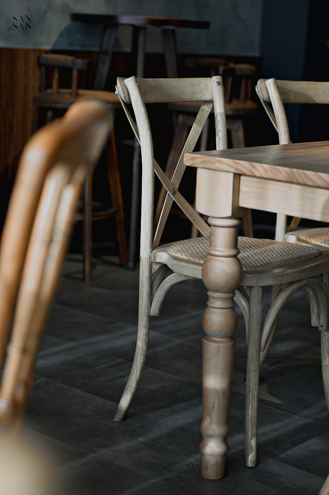 陽光灑在造型木桌桌腳 和藤編木椅的畫面