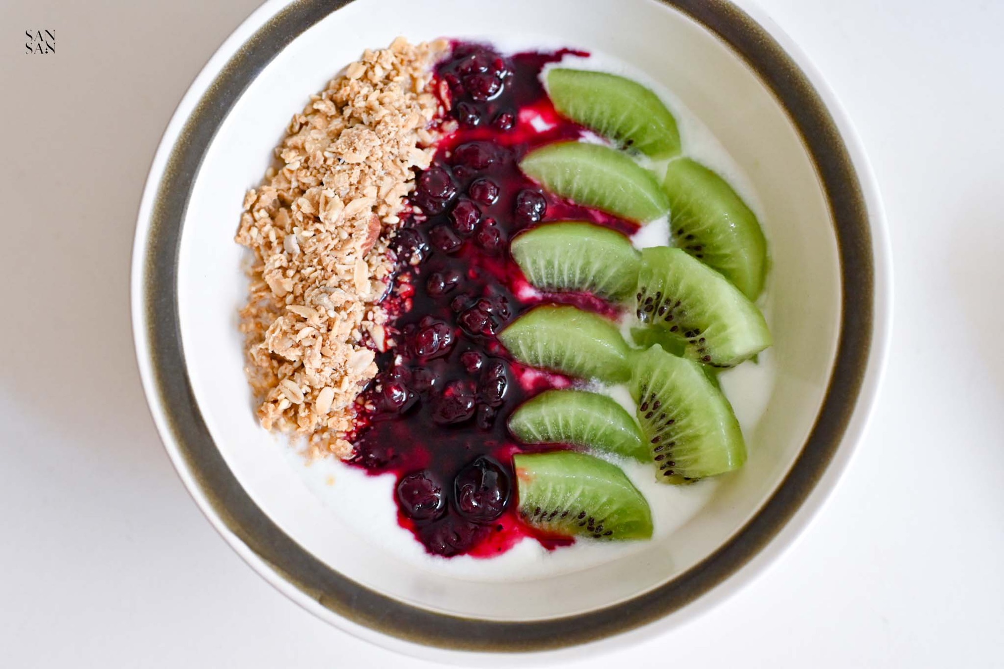 水果優格碗，整齊擺放燕麥碎、綜合梅果果醬以及奇異果丁