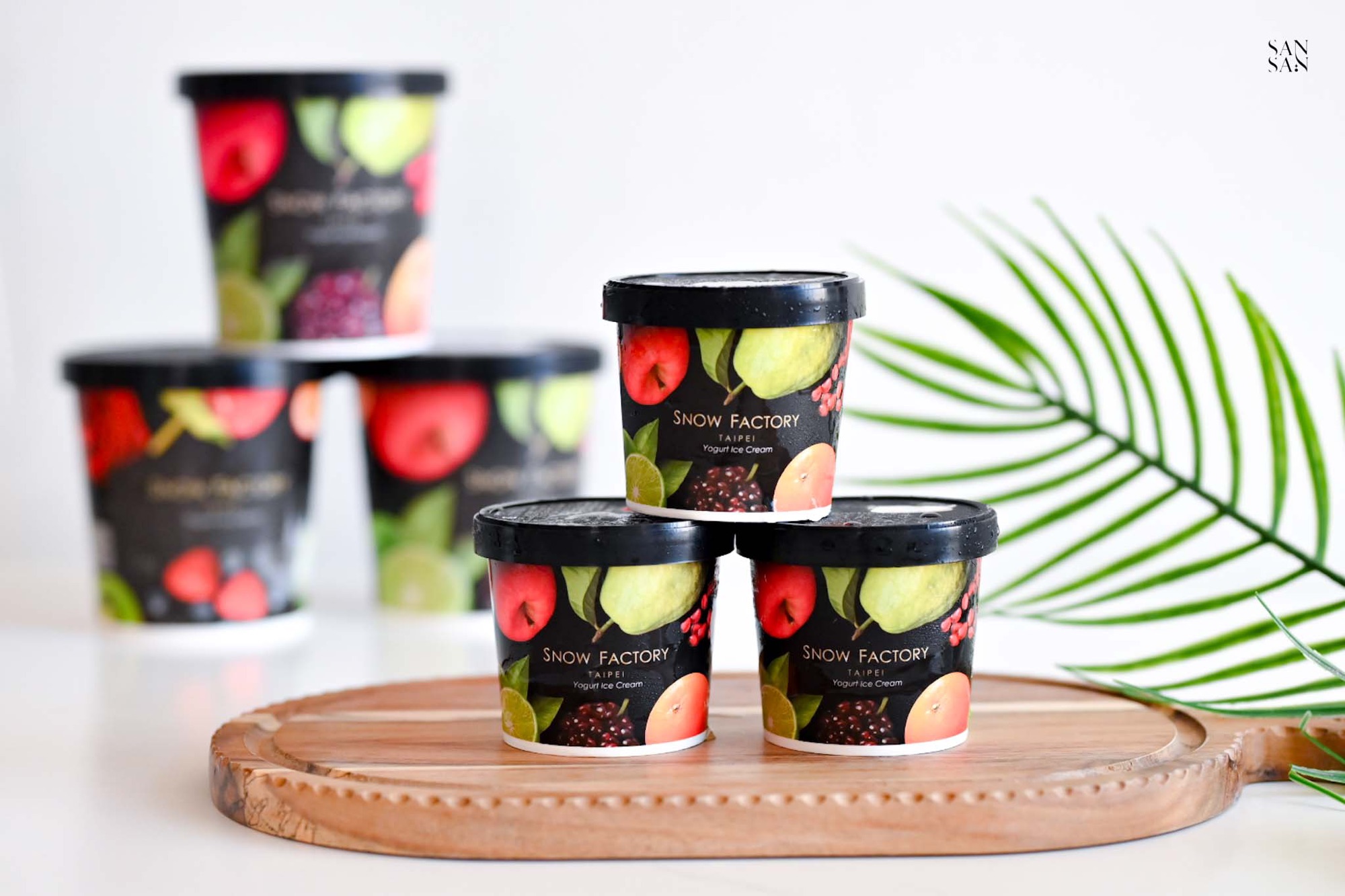 三罐獨享杯120ml的雪坊頂極優格冰淇淋，以金字塔造型疊放在桌上的木頭托盤