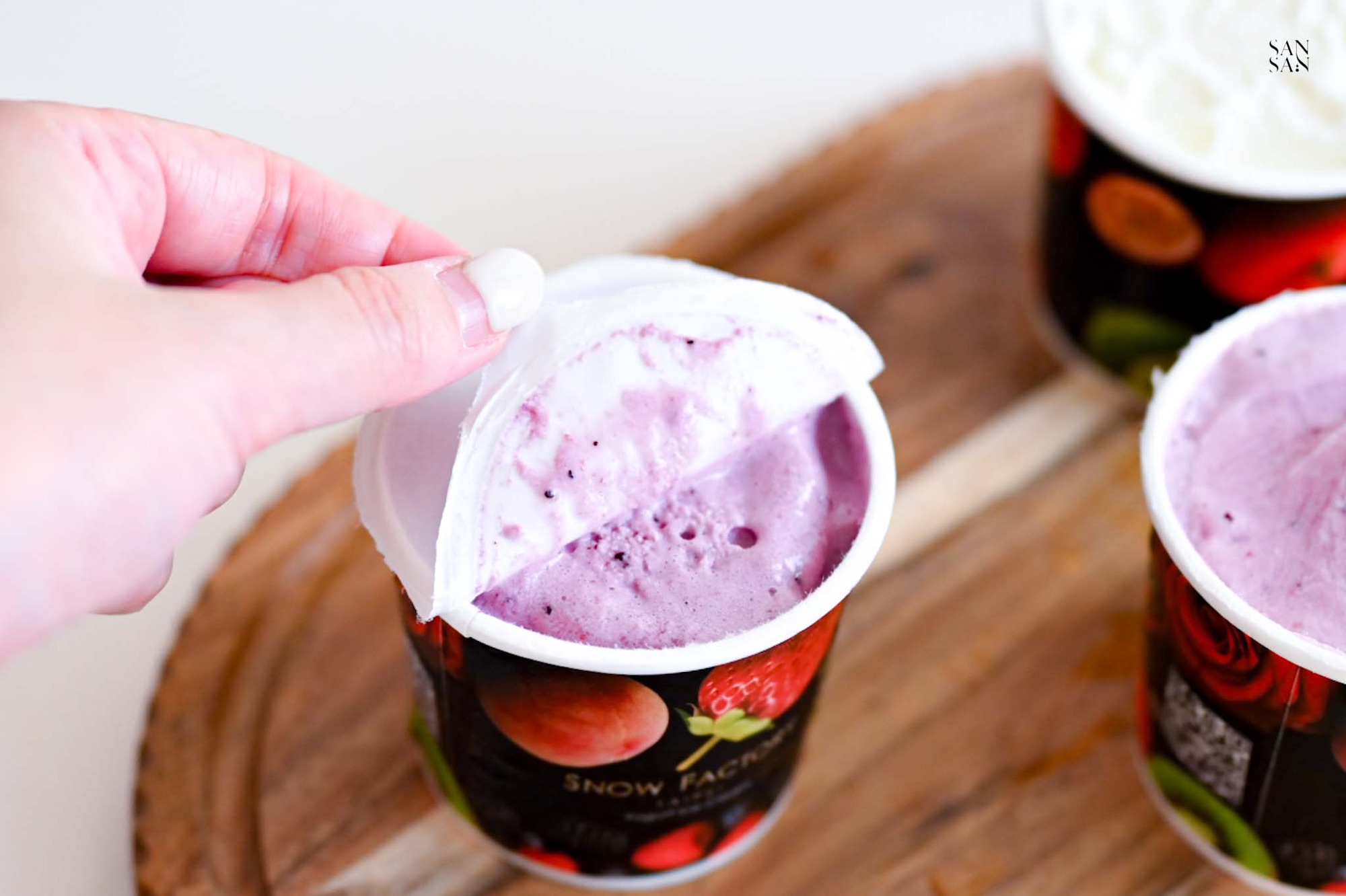 我正在撕開冰淇淋杯上的薄膜，杯子內是紫紅色的藍莓優格冰淇淋