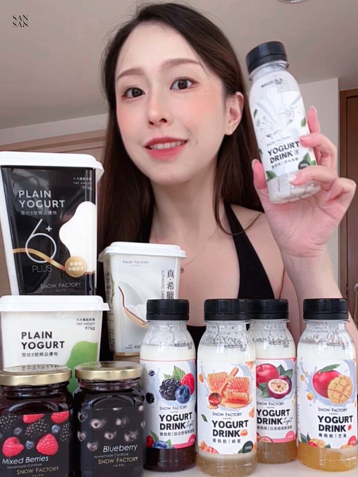 sansan微笑地拿著原味無糖優格飲，和桌上的雪坊團購商品合照。