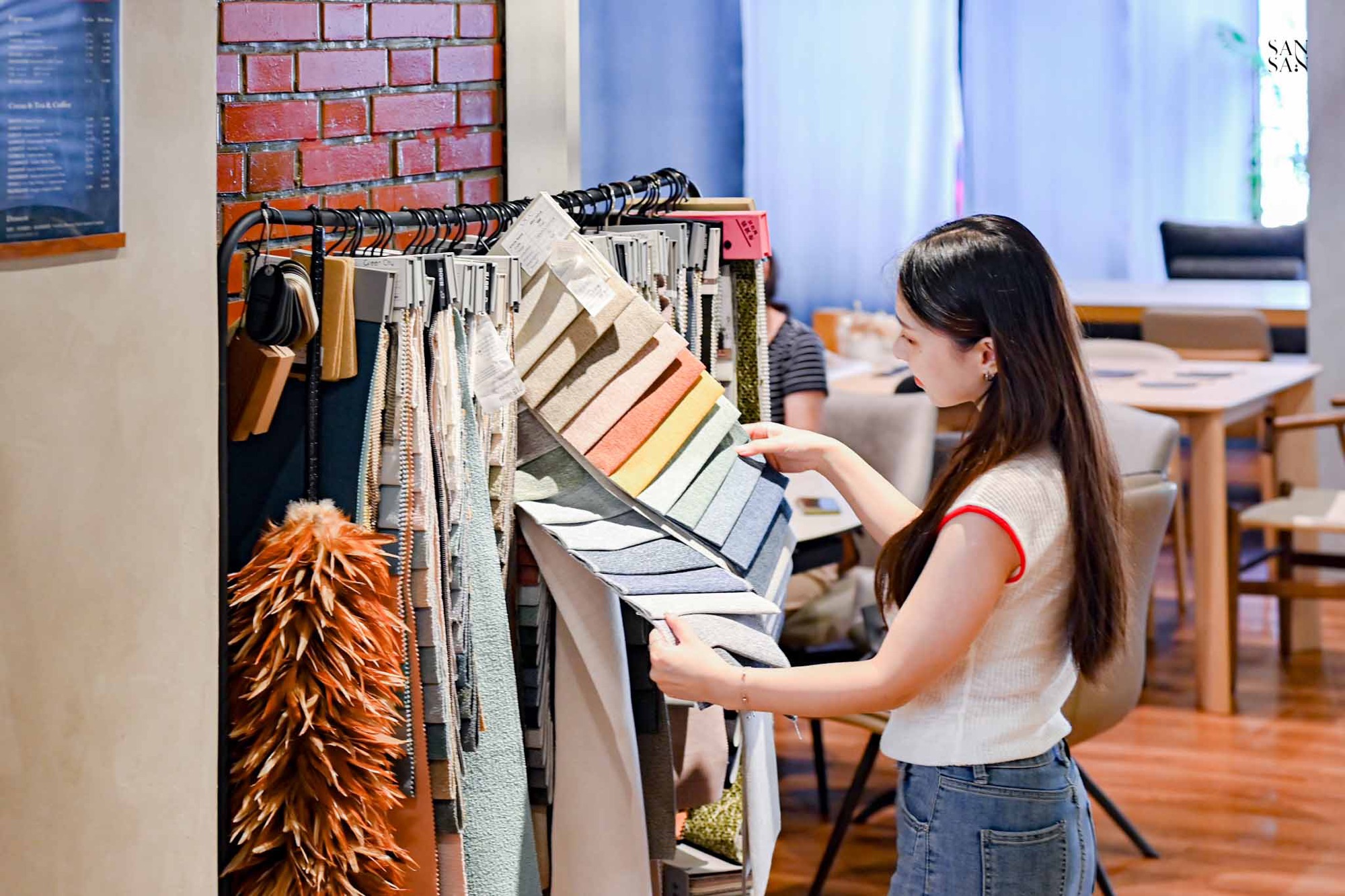我在掛滿各種材質與顏色的布料展示架前挑選布料