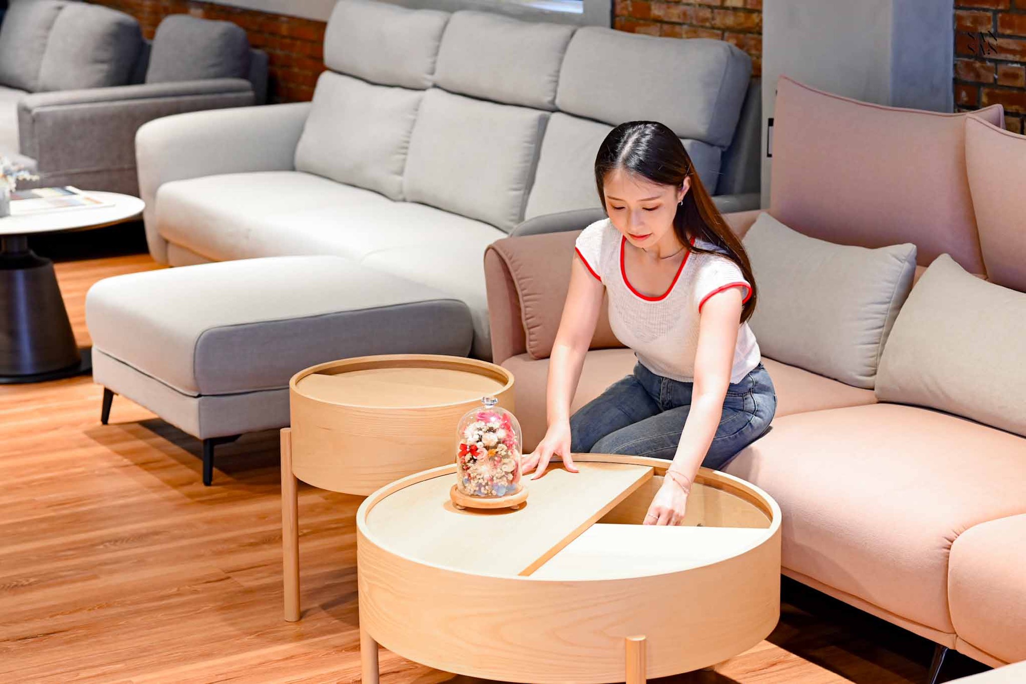 我正在體驗可透過旋轉桌面半圓形木闆，開啟收納空間的木頭圓形茶几